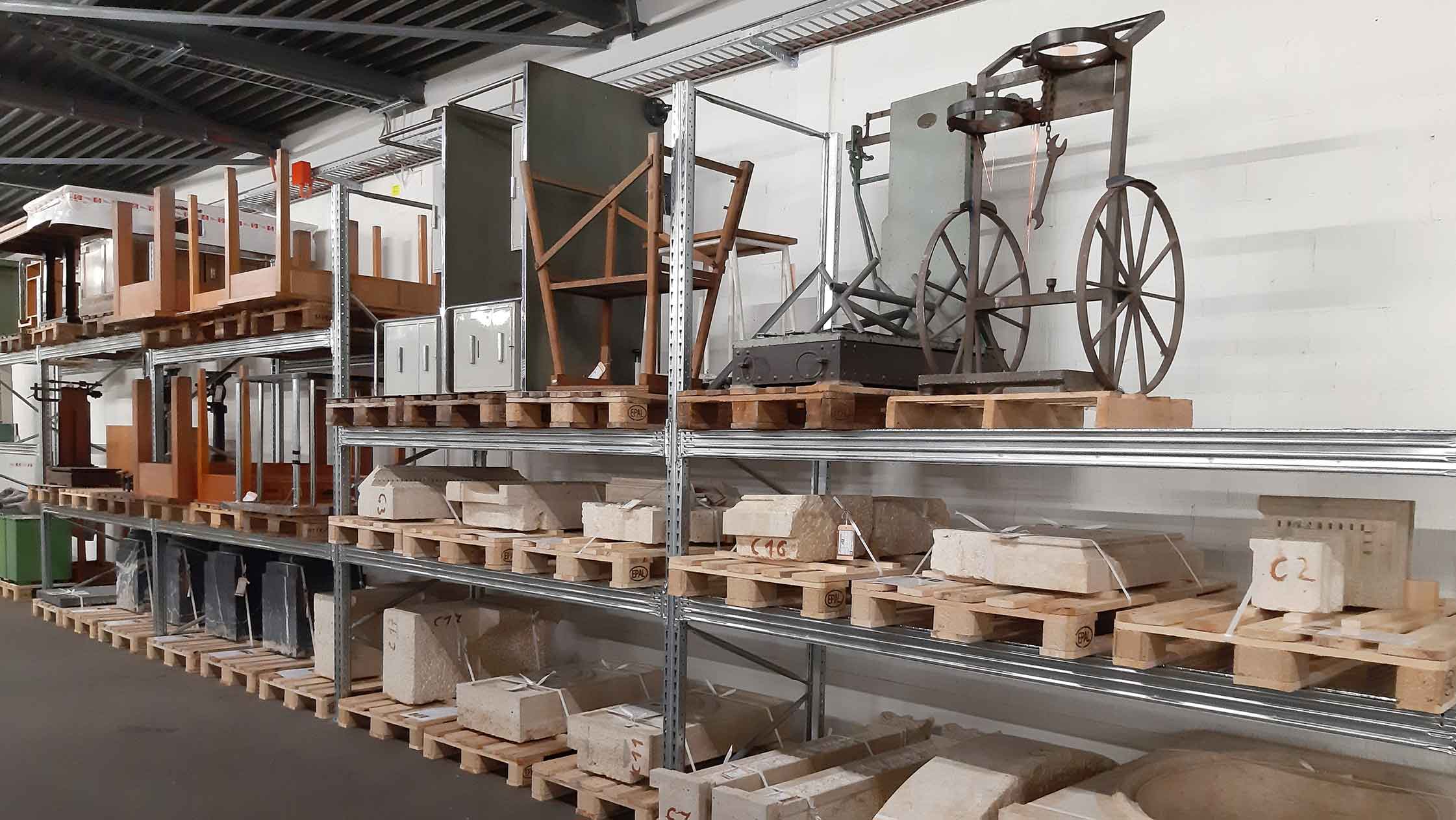 Das Foto zeigt ein Regal mit verschiedenen Objekten wie Tischen der Sammlung «Bestände der Baukultur ETH Zürich».