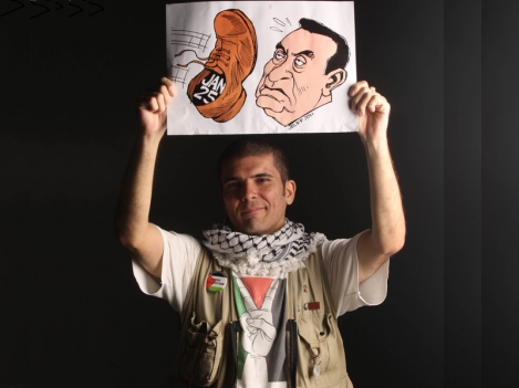 Enlarged view: Brazilian cartoonist Carlos Latuff upholding one of his cartoons on Egypt