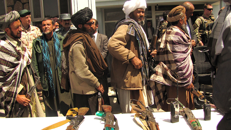 Former Taliban fighters line up to handover their Rifles