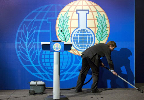 A cleaner vacuums the stage prior to an OPCW news conference at the Bel Air Hotel in The Hague October 11, 2013. Reuters / Michel Kooren.