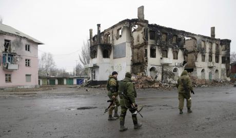 Pro-Russian rebels walk past a destroyed building in Vuhlehirsk