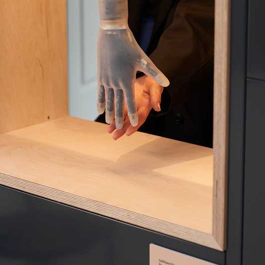 Bionische künstliche Hand, die einen mit kleinen Kugeln gefüllten Becher ergreift, ohne ihn zu zerdrücken und die Kugeln zu verschütten