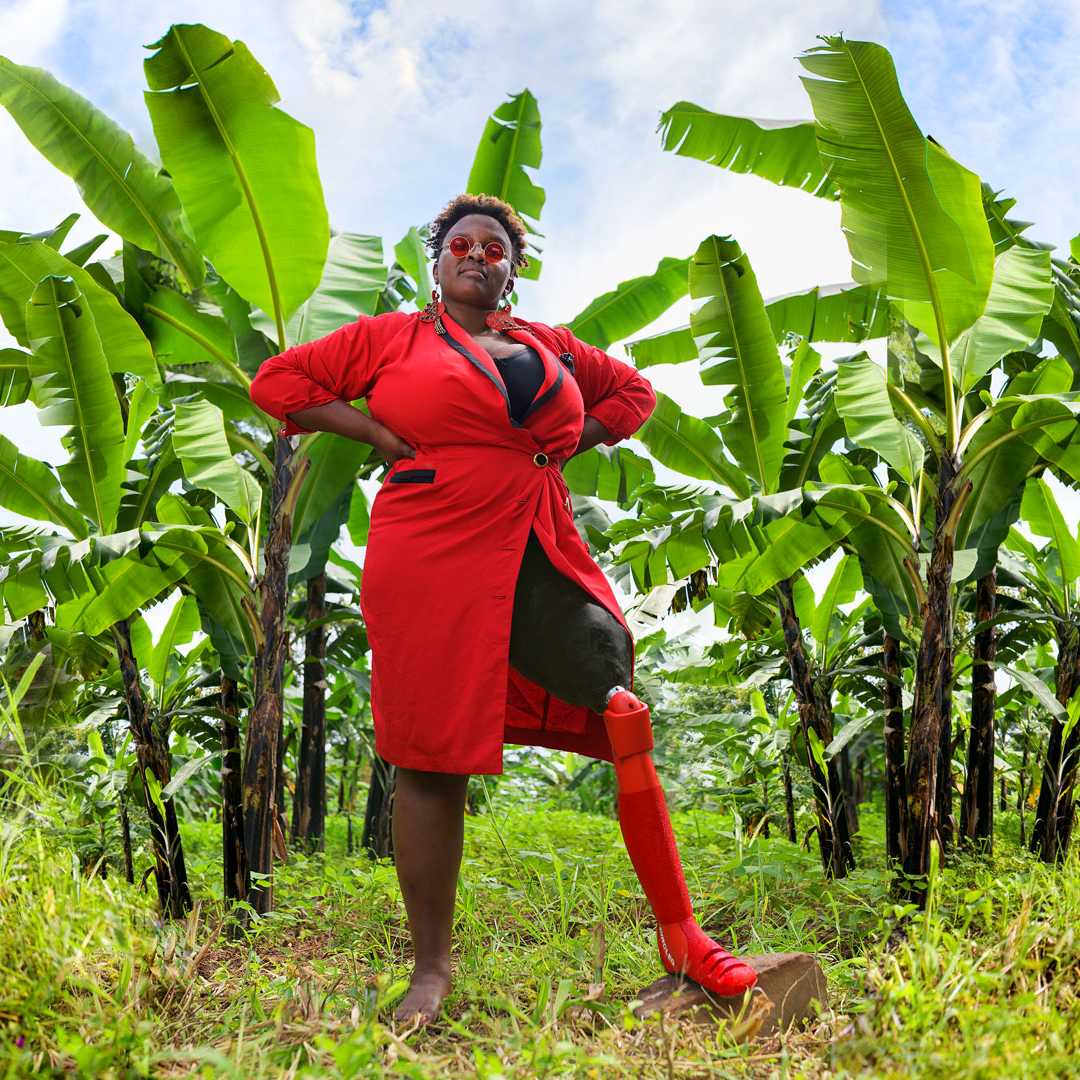 Frau aus Uganda in einem roten Kleid, die eine rote Prothese trägt  
