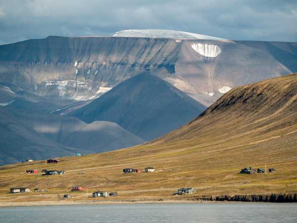 Vergrösserte Ansicht: Flacher Abhang mit Häusern, im Hintergrund Berg mit Eisschild