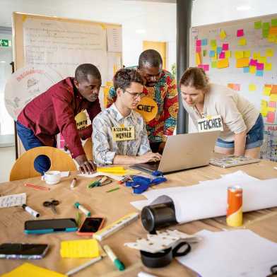Ghanaische und Schweizer Studierende betrachten etwas auf einem Laptop