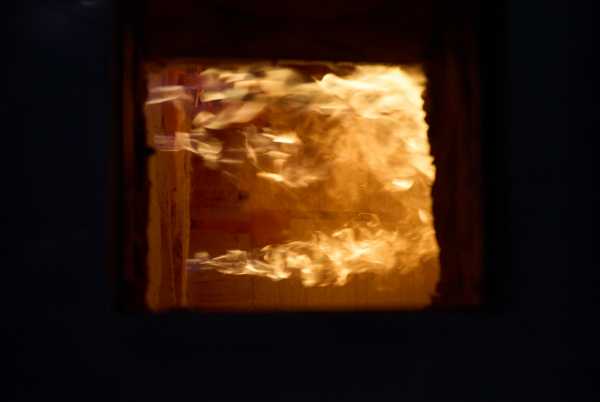 Guckloch in den Ofen ein während des Betriebs. Es sind Flammen sichtbar.