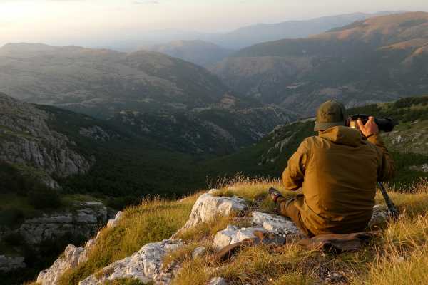 Person mit einer Kamera auf einem Berg beim beobachten der Landschaft