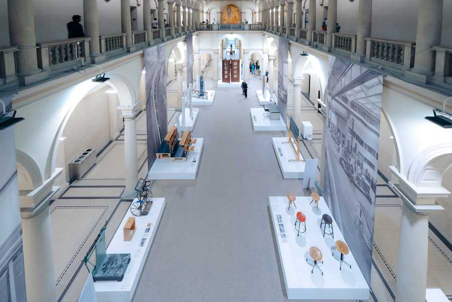 Vergrösserte Ansicht: Bild von der Galerie auf die Eingangshalle hinunter, in welcher die Ausstellung zu sehen ist.