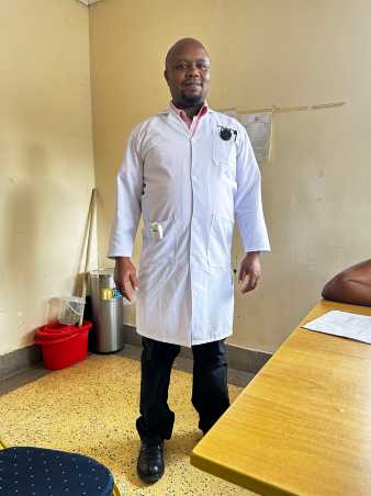 Ein afrikanischer Arzt in weissem Kittel welcher den Sensor trägt