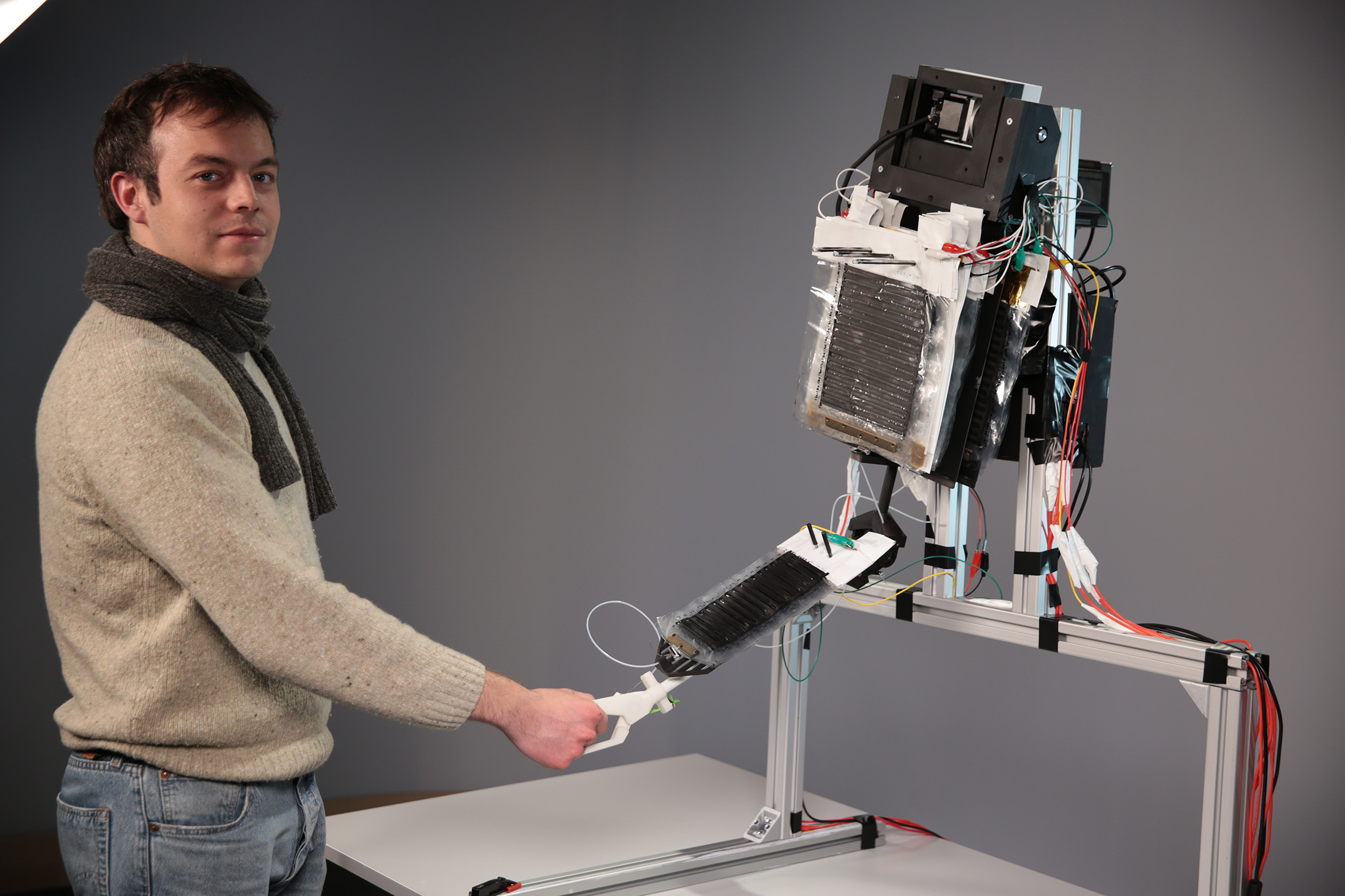 Ein Studierenden schüttelt dem Roboterarm die Hand