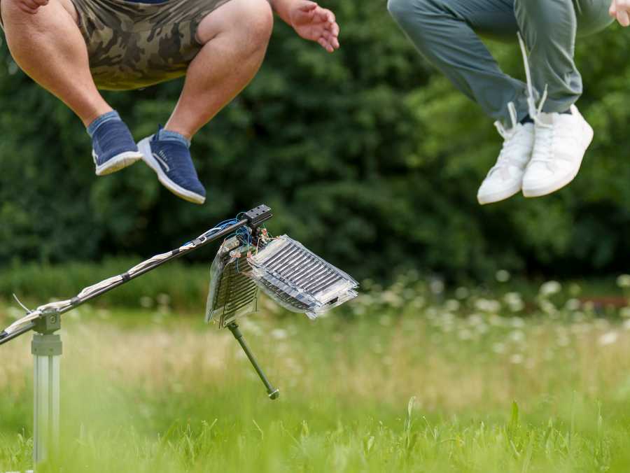 Vergrösserte Ansicht: Die Forscher sind springend in der Luft, vor ihnen steht das Roboterbein