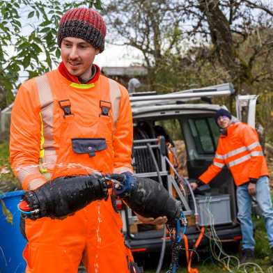 Mann in orangem Overall hält die beiden Dichtungselemente in der Hand