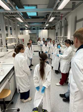 Kinder besuchen ein Labor. Sie tragen alle Laborkittel.