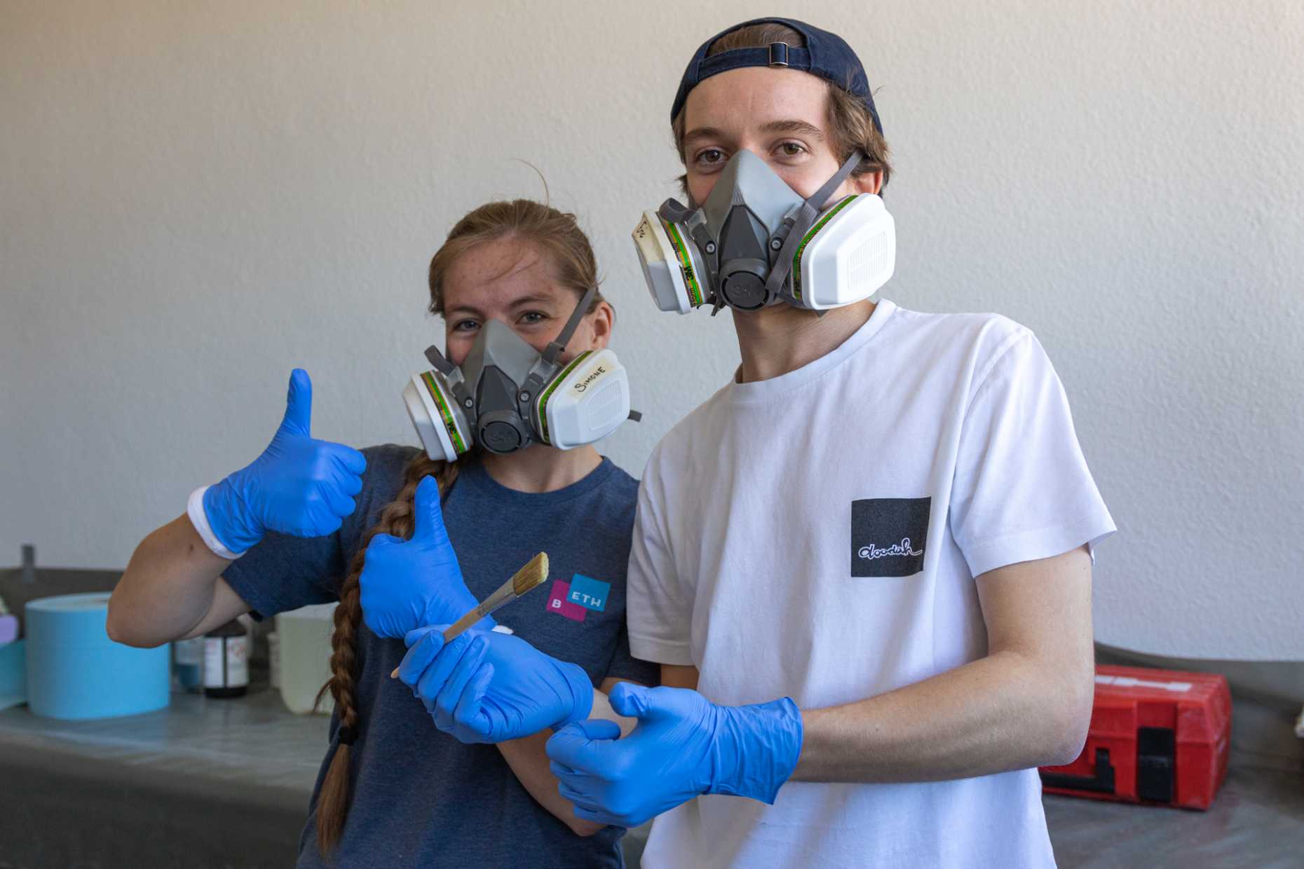 Eine Studentin und ein Student mit schützenden Masken und Handschuhen