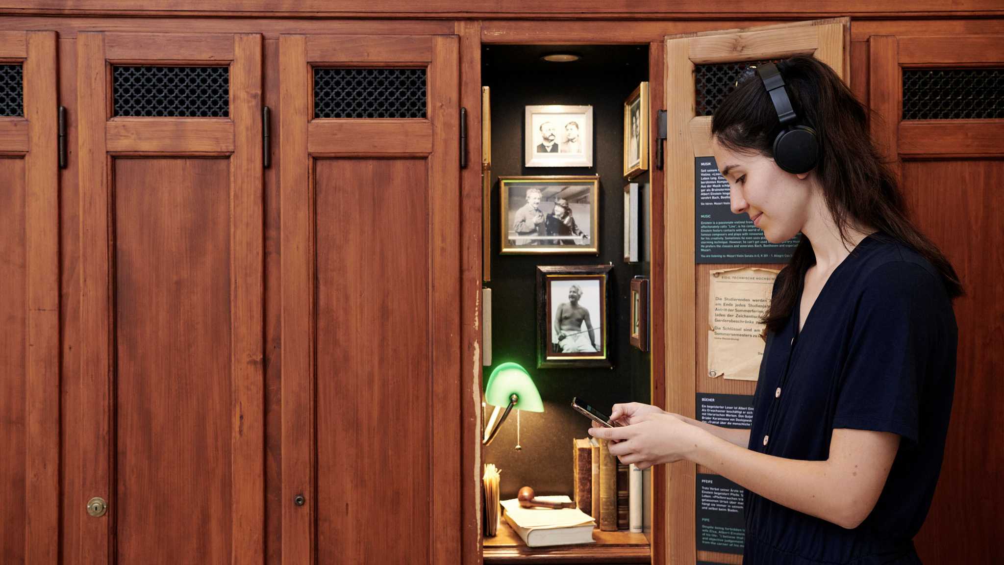 A visitor with mobile phone and headphones in front of Albert Einstein's locker