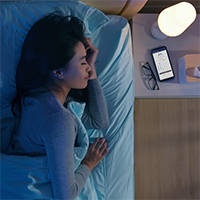 woman sleeping with active app on smartphone on bedside table