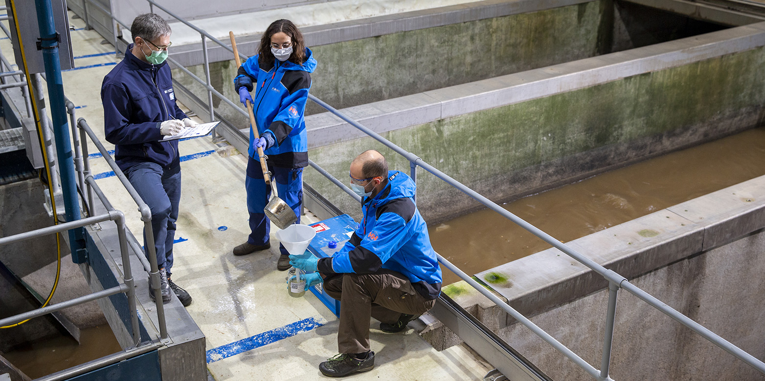 three researchers taking samples and notes at a sewage plant