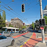 road junction with cars, cyclists, bus and traffic lights