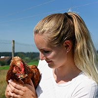 woman holding hen with a cricket in its mouth