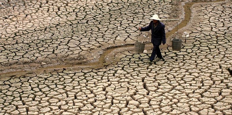Enlarged view: Chinese farmer looking for water in a dry river bed.