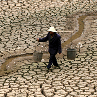 Chinese farmer looking for water in a dry river bed.