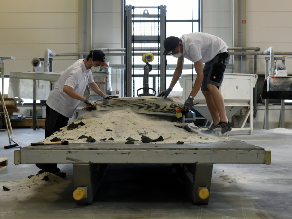 Post-processing of the 3D printed formwork parts. Unconsolidated sand particles are being removed from the print bed. (Photograph: ETH Zurich / Tom Mundy)