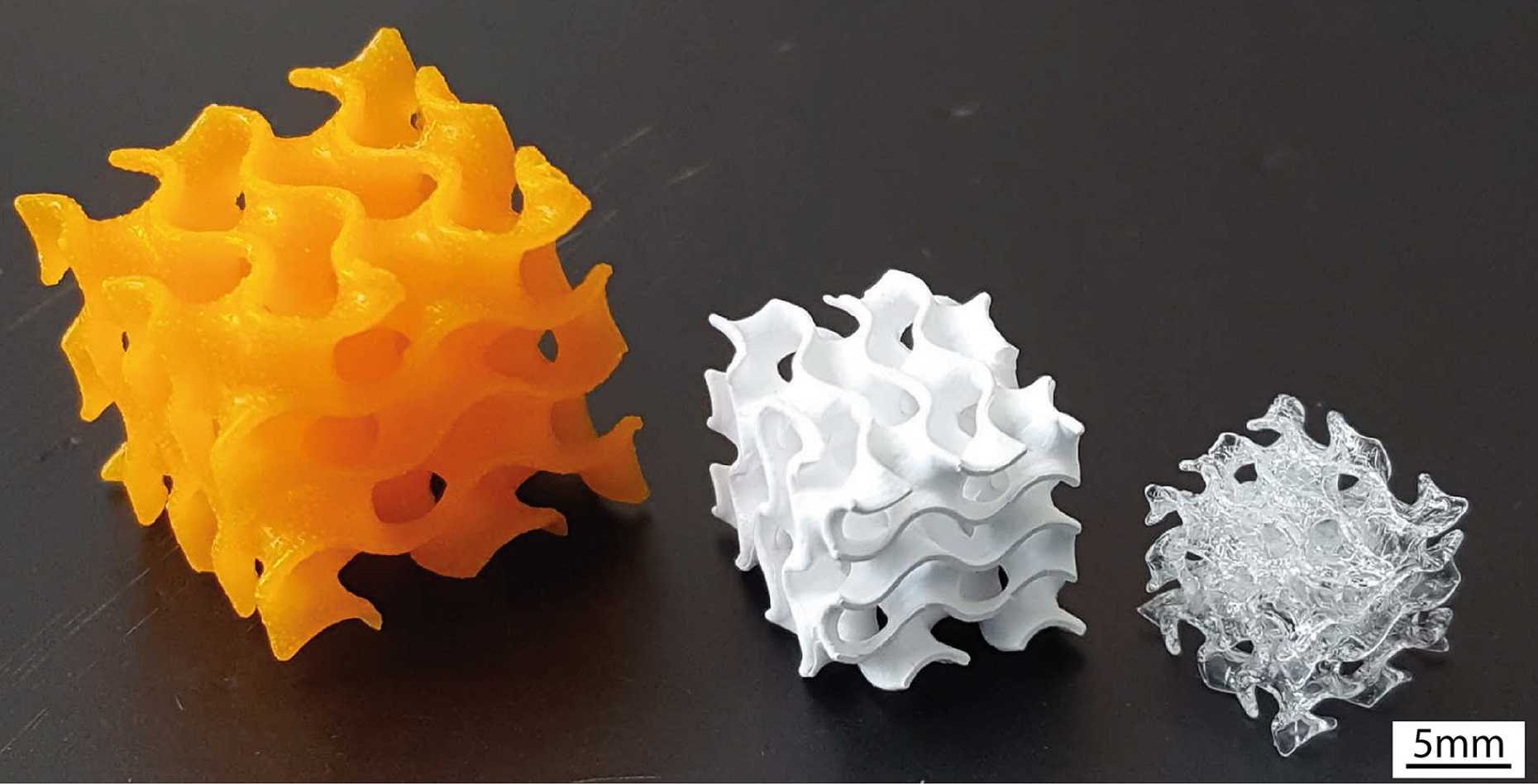 On the left, the 3D-printed block is orange and plastic-looking. In the center, the block is smaller and white. On the right, the block is smaller and glassy