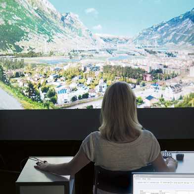 Woman sitting in virtual reality lab with landscape images