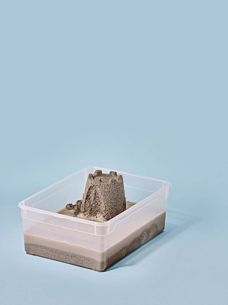 A collapsed sand castle in a plastic box