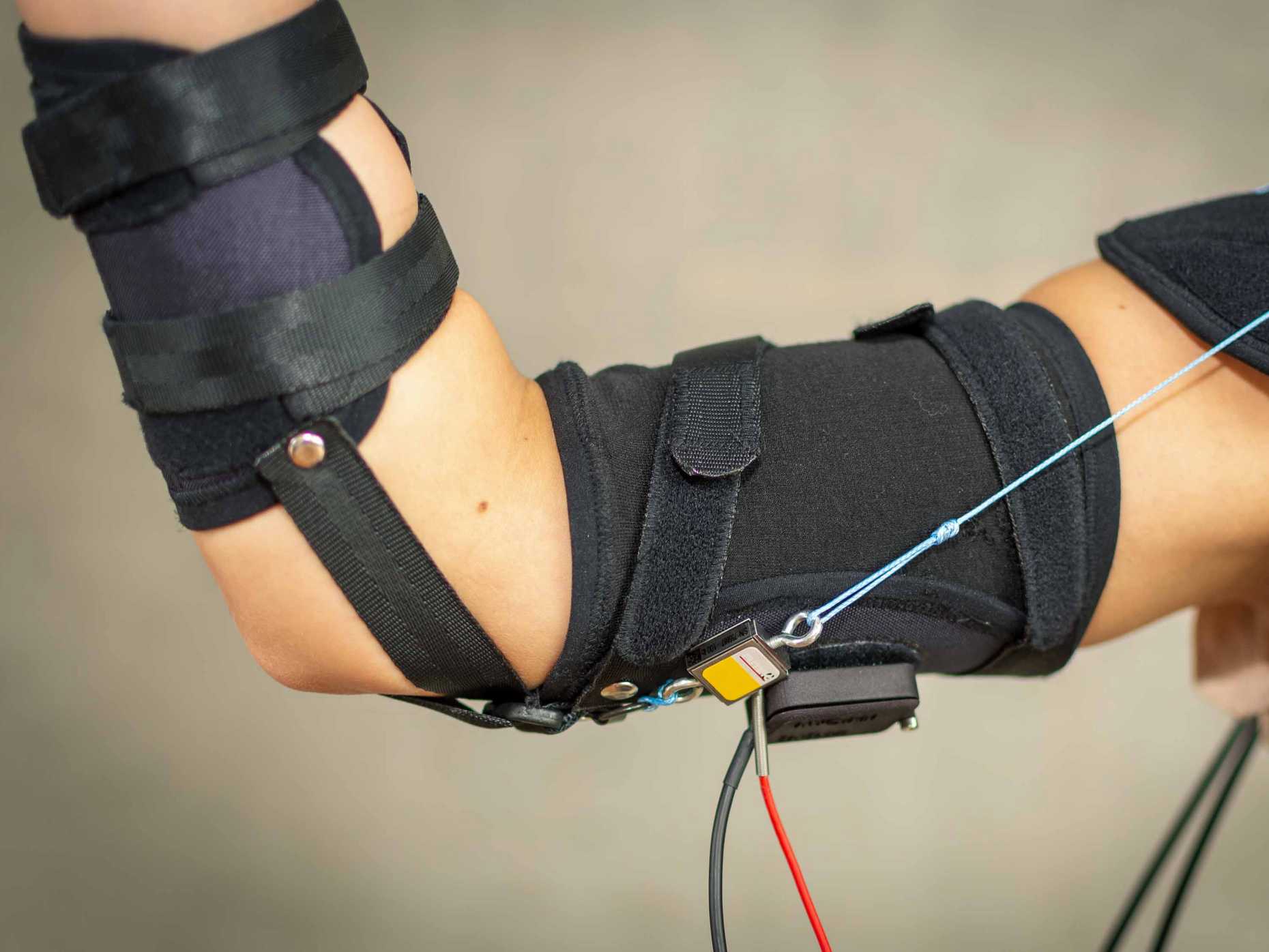 A researcher flexes their bicep while wearing the cuff of the exomuscle.