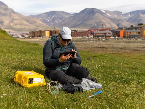 Enlarged view: Researcher sitting with equipment in a meadow