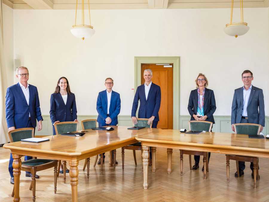 Enlarged view: The contracting parties stand in front of a table with the contracts