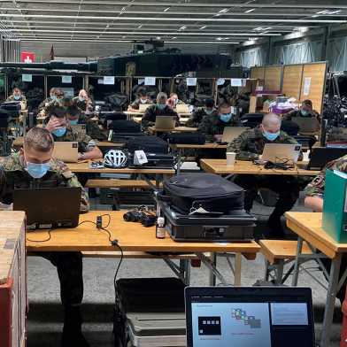 Swiss Army officers working on laptops in a hall