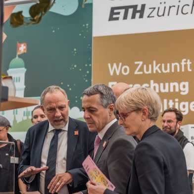 Detlef Günther stands with Ignazio Cassis and another woman in front of the "start-up tower" of the ETH stand and talks. 