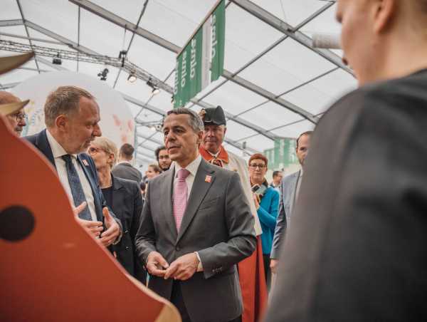 President Ignazio Cassis (right) chats with Detlef Günther (left). The two are surrounded by many people.