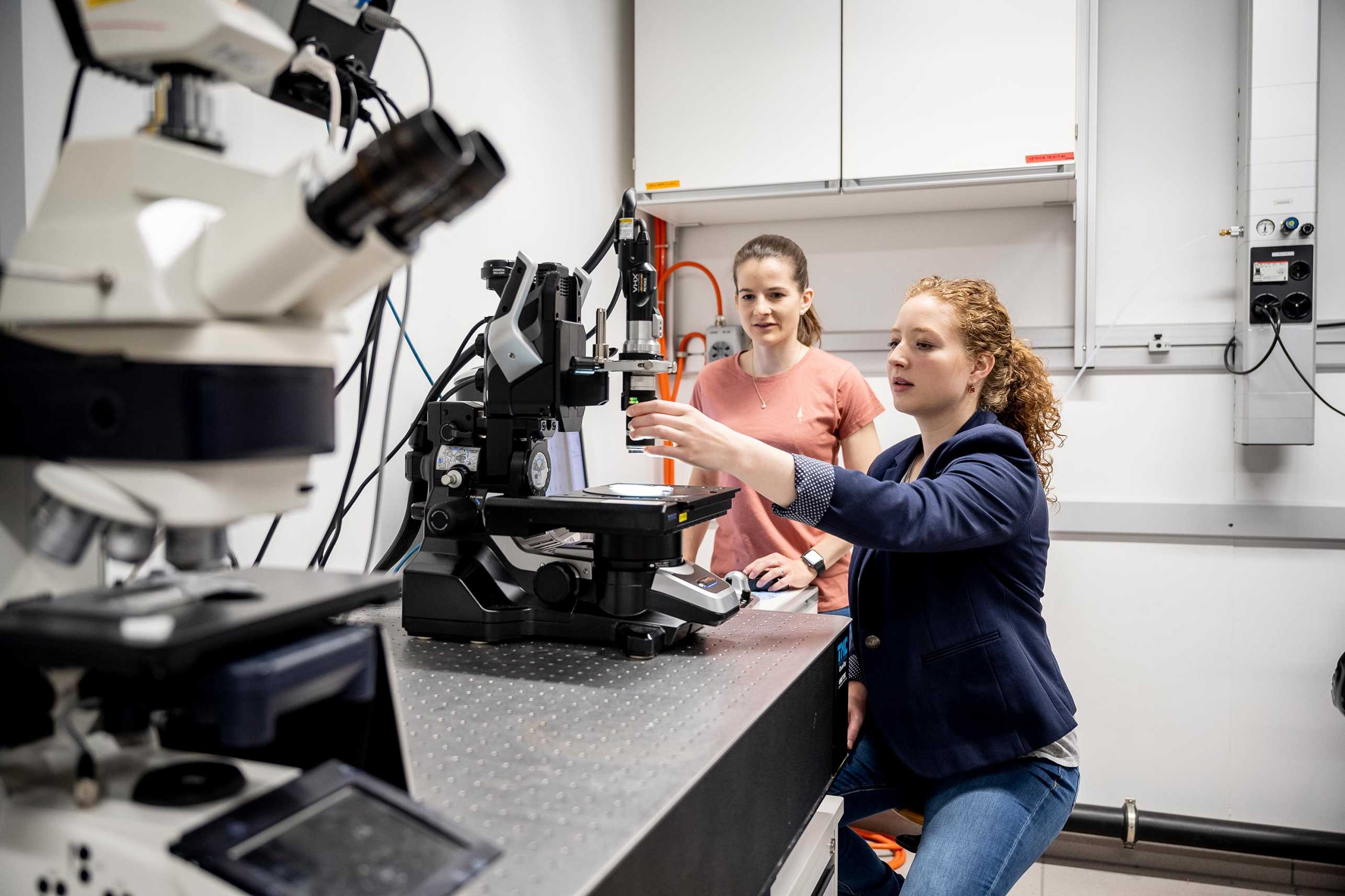 Nicole Kleger and Simona Fehlmann in the lab, working with a microscope