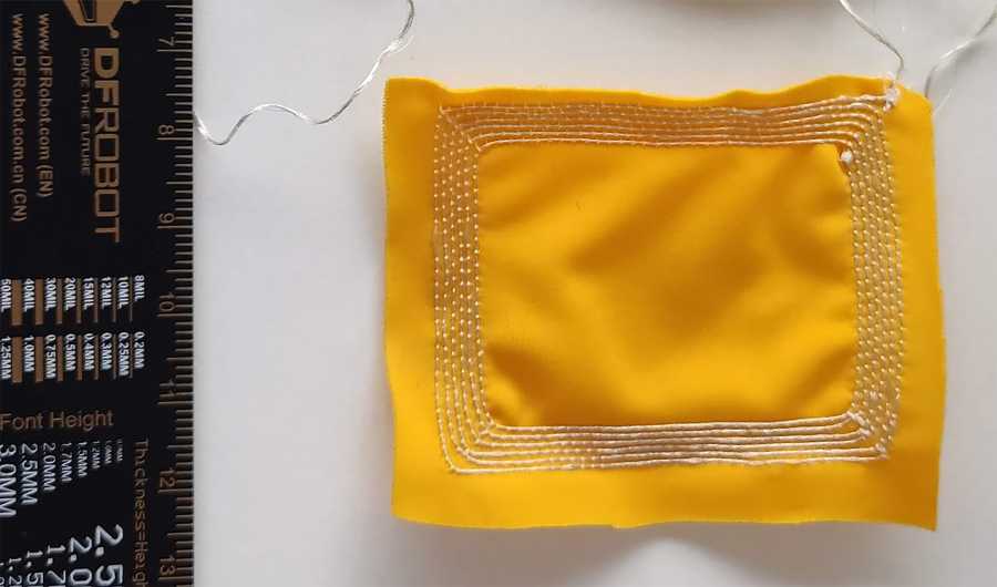 Enlarged view: A yellow piece of fabric with the antenna embroidered on it.
