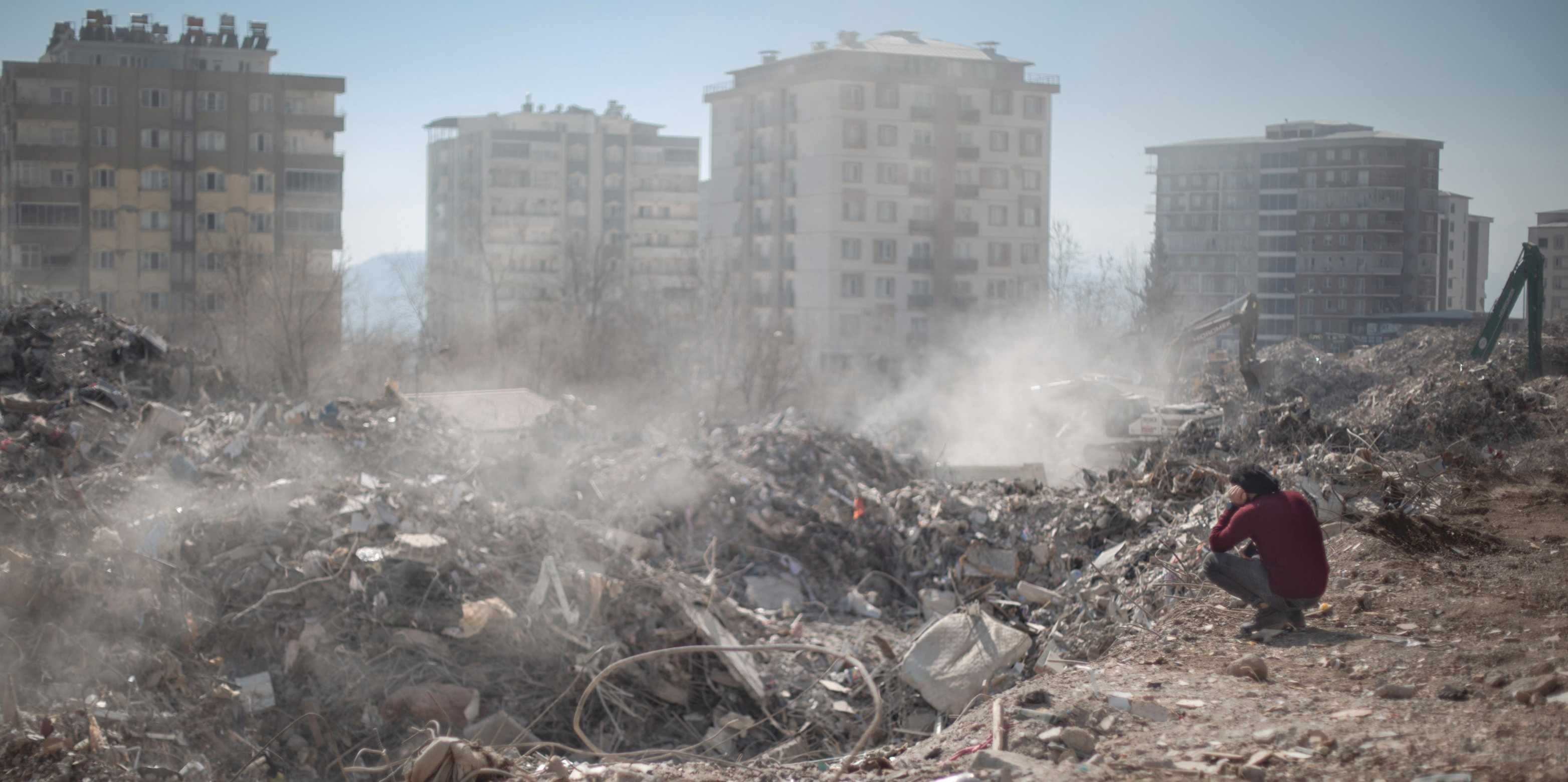 Umgebung der Türkei nach dem Beben. Ein Mann kniet vor den Trümmern.