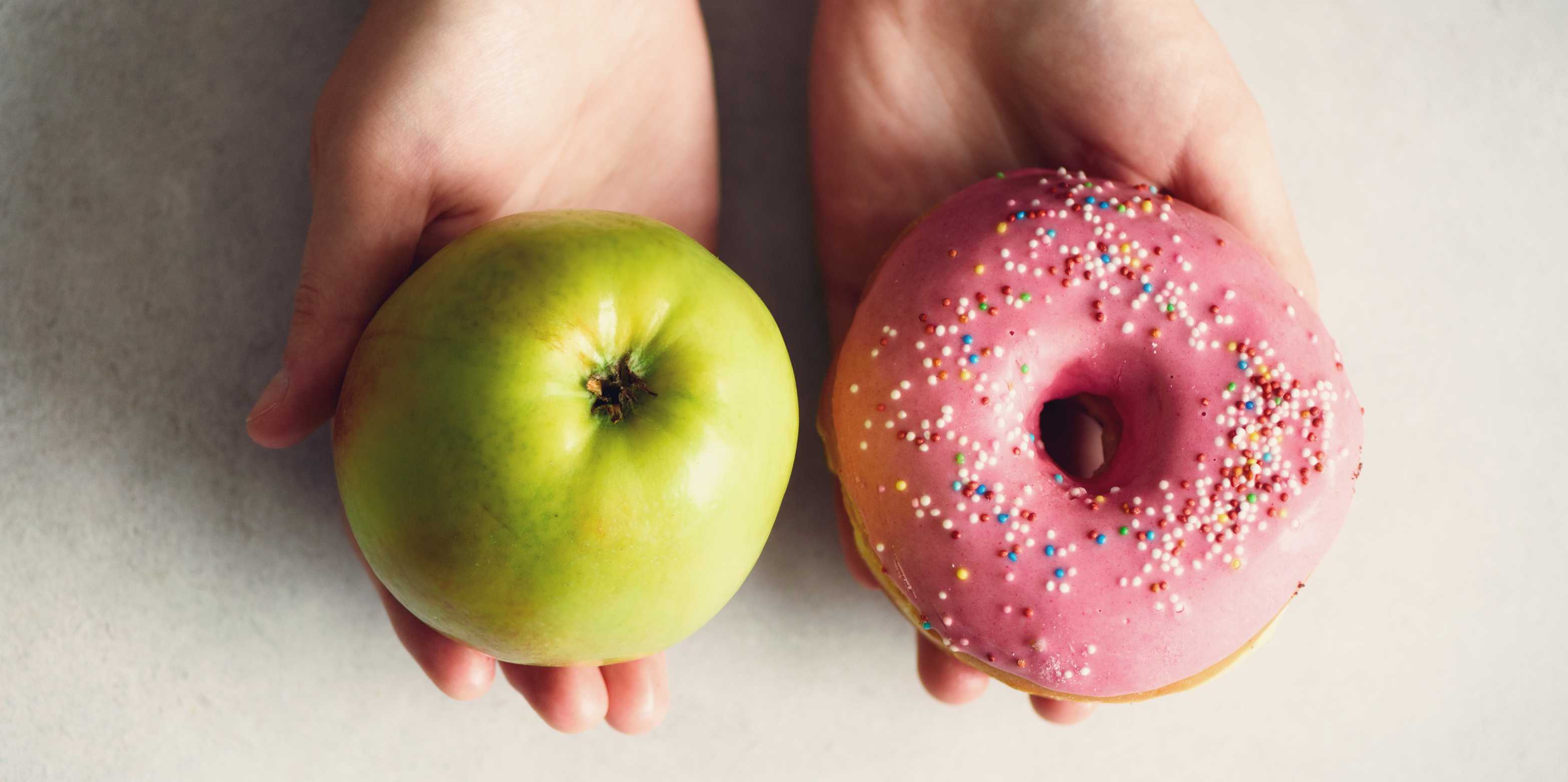 One person presents an apple on one hand and a donut on the other.