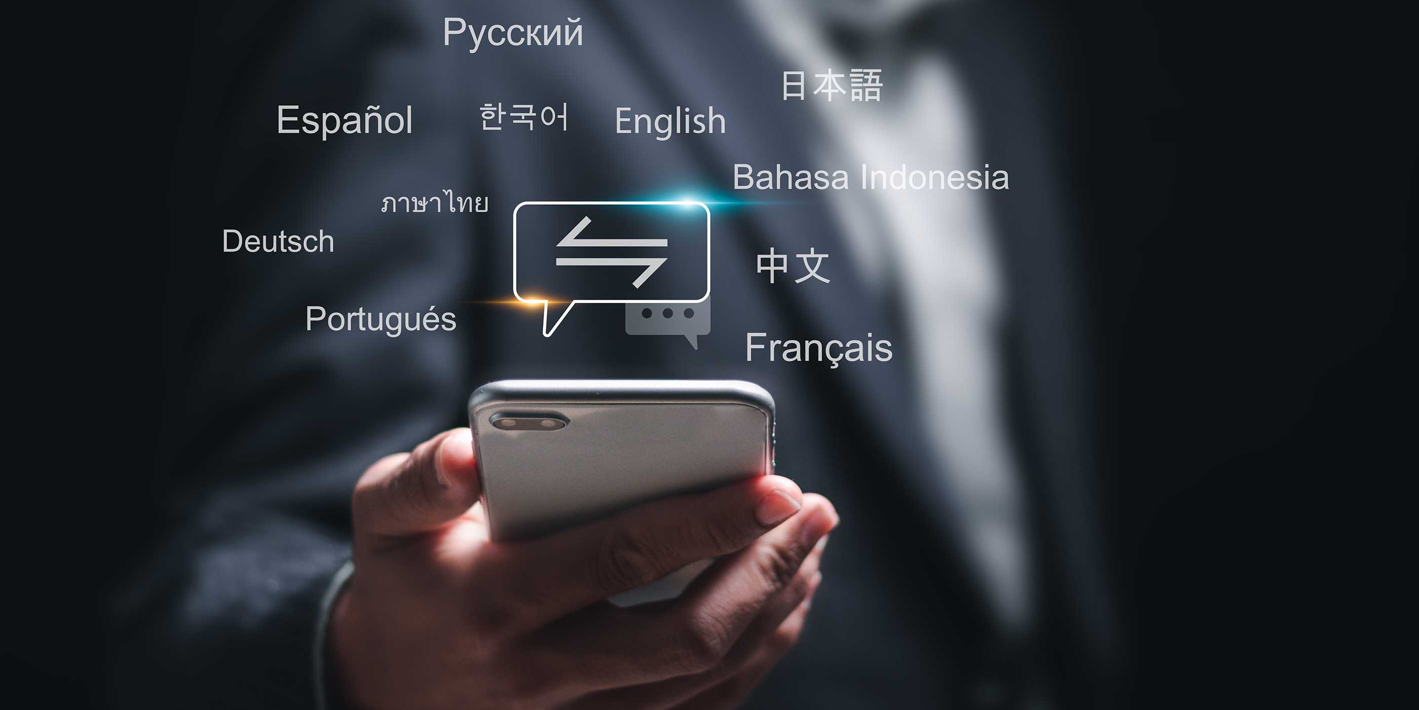 Hand holding a smartphone, words in different languages appear in the air above it