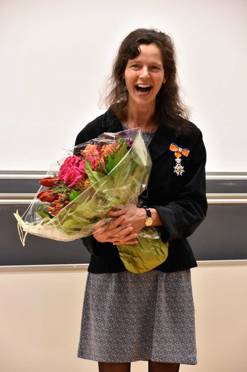 Sara van de Geer with a bouquet of flowers in her hand, her mouth open with joy. A medal is pinned on her jacket.