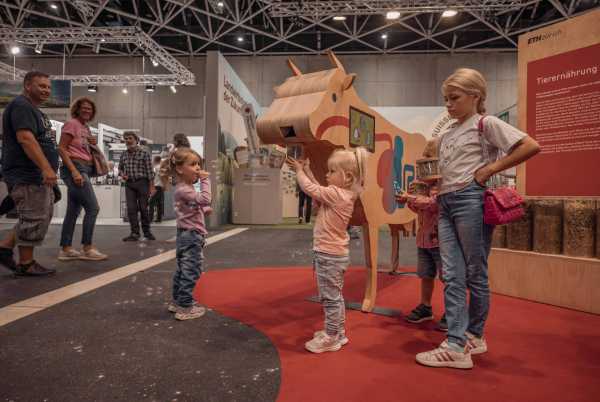 Several children look at a wooden cow