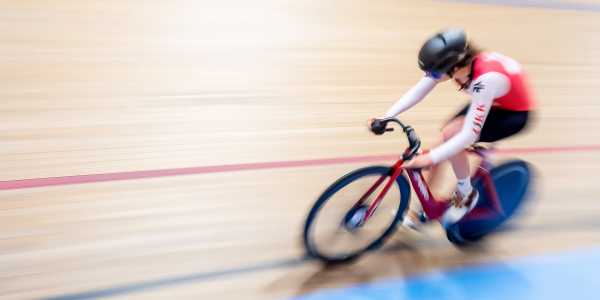 A woman on a racing bike on an indoor cycling track.