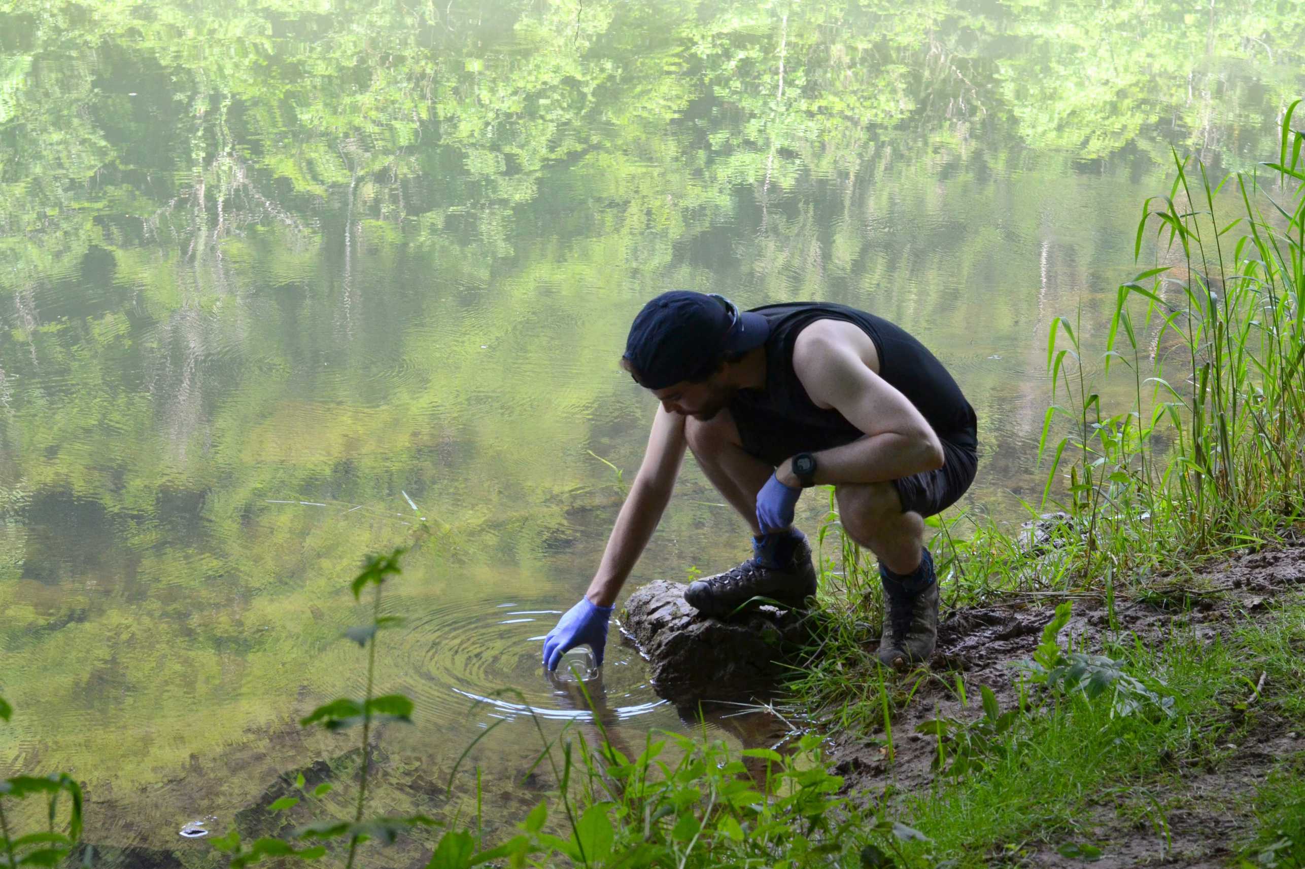 Person at the river takes a sample.