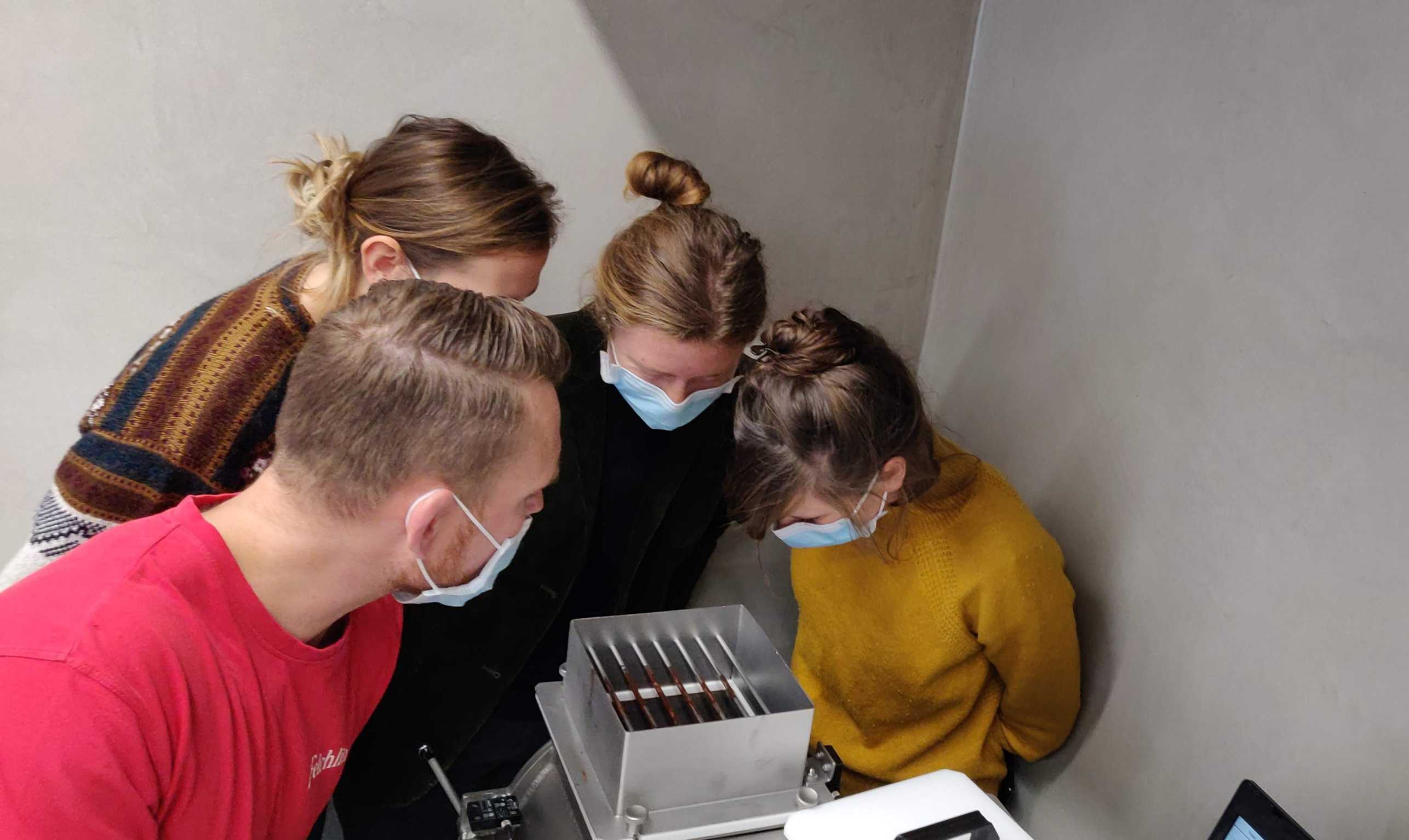 The researchers in the laboratory look into a box in which a process takes place.