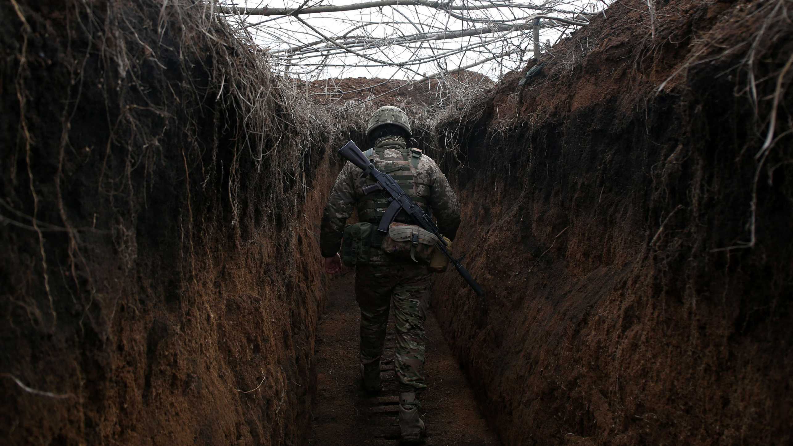 A Ukrainian soldier walking through a trench