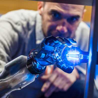 A man assembling a blue glowing lamp with a robotic hand.