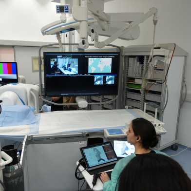 A surgeon in the operating theater is sitting in front of a screen showing the live feed from Zurich.