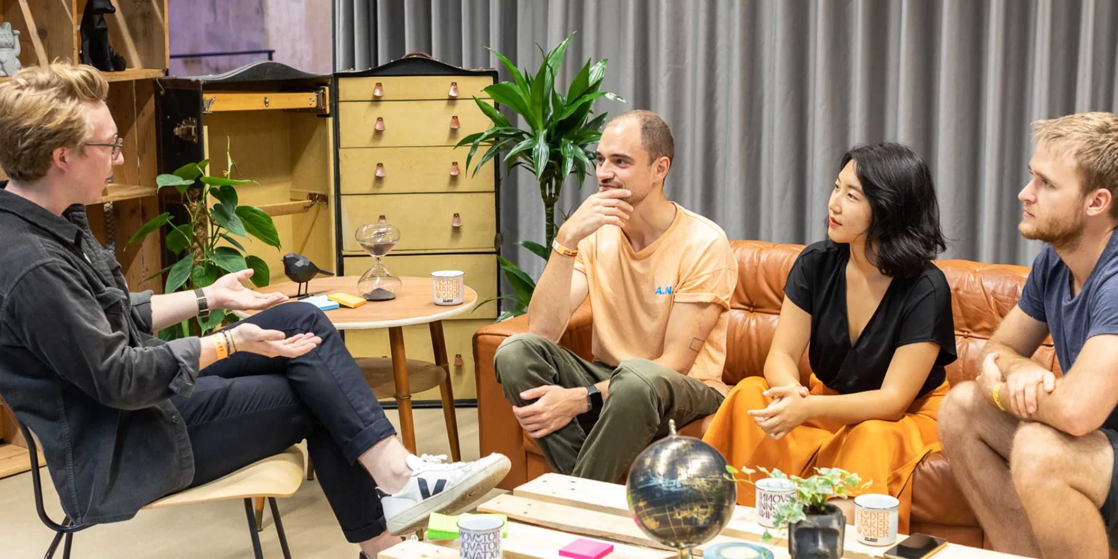 Four people sitting around a table talking in the Student Project House