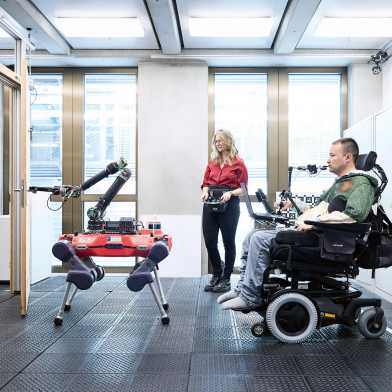 A four-legged robot opens the door for a man in a wheelchair